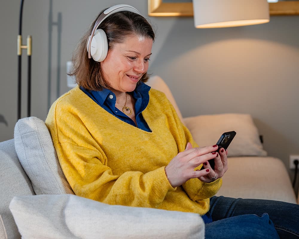Frau hört mit Kopfhörern entspannt auf dem Sofa ein MIND-Audio