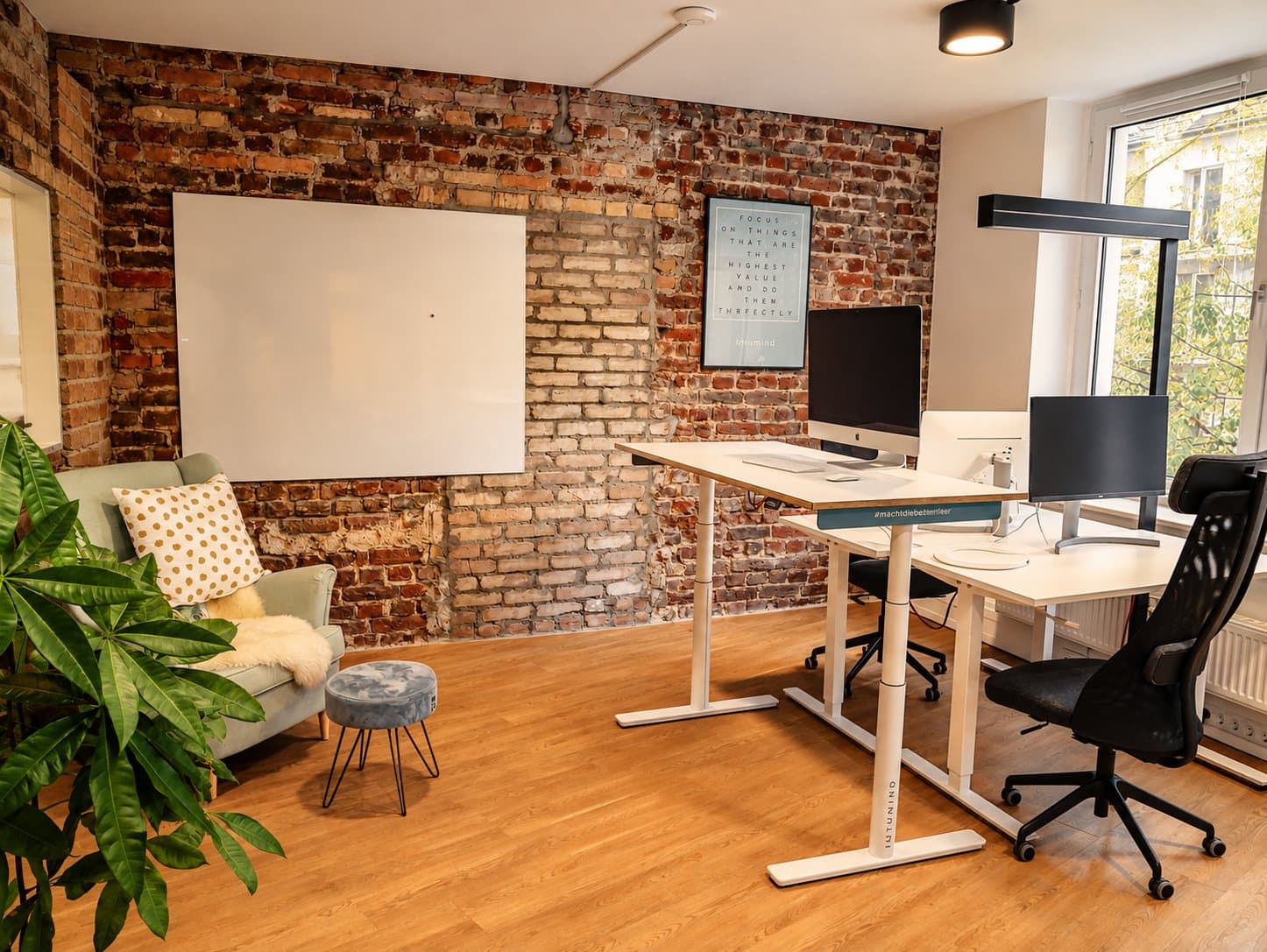 Arbeitsplatz vor freigelegter Klinkerwand mit Whiteboard
