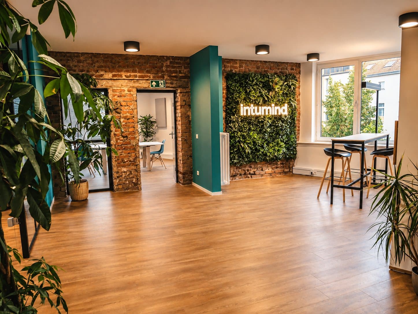 Community-Fläche des Loft-Office mit grüner Pflanzenwand und Klinkerwand